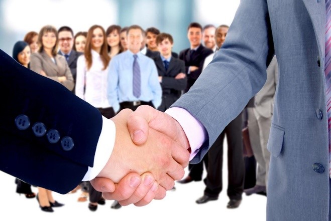 Professional handshake with a diverse business team in the background